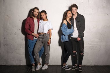 Ciddi hipsters gri arka plan üzerinde duran çiftler sevgi dolu.