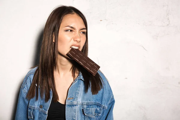 怒っている流行に敏感な女性がチョコレートを食べる — ストック写真