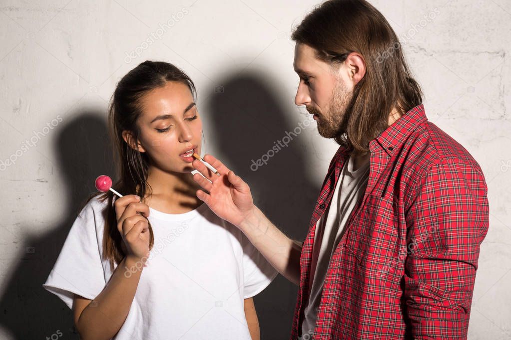 Man standing over gray background give cigarette to girlfriend