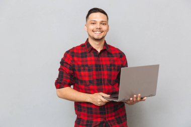 Ekose gömlekli dizüstü tutan genç bir adam portresi