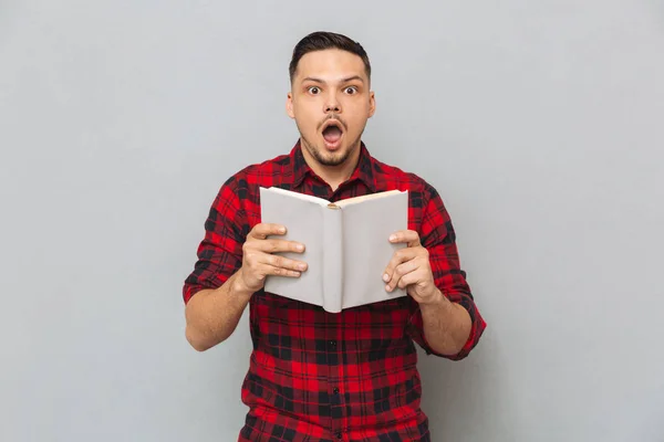 Schockierter Mann hält Buch in Händen — Stockfoto