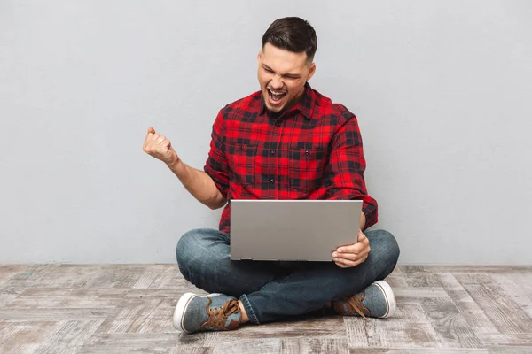 Retrato de un joven usando laptop y celebrando el éxito —  Fotos de Stock