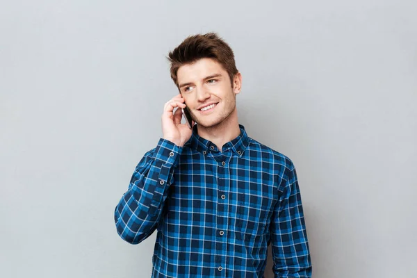 Hombre guapo de pie sobre la pared gris y hablando por teléfono . —  Fotos de Stock
