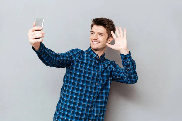 Joven saludo con alguien mientras hace videocall o selfie — Foto de Stock