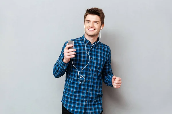 긍정적인 남자 춤 동안 스마트폰에 듣는 음악 — 스톡 사진