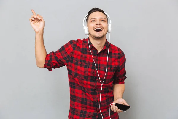 Vrolijke jonge man luisteren muziek met koptelefoon. — Stockfoto