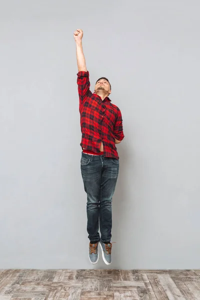 Joven concentrado saltando sobre la pared gris . — Foto de Stock