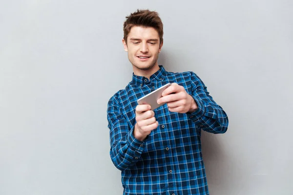 Молодой человек играет в игры на смартфоне — стоковое фото