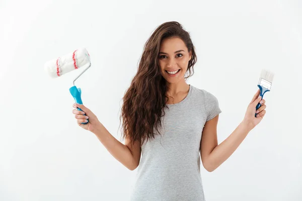 Cheerful attractive young woman with brush and paint roller — Stock Photo, Image