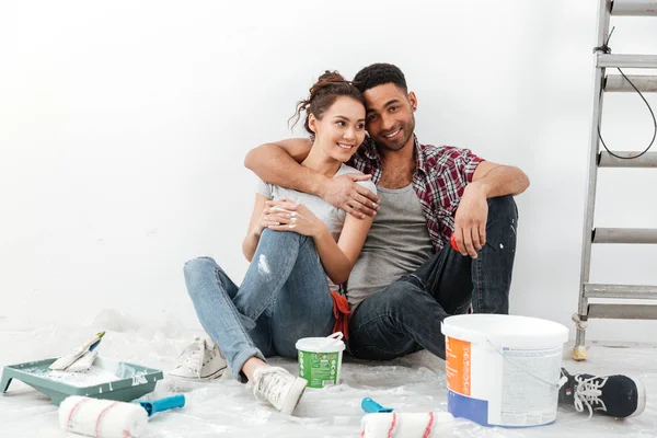 Feliz multiétnico jovem casal renovando casa e abraço — Fotografia de Stock