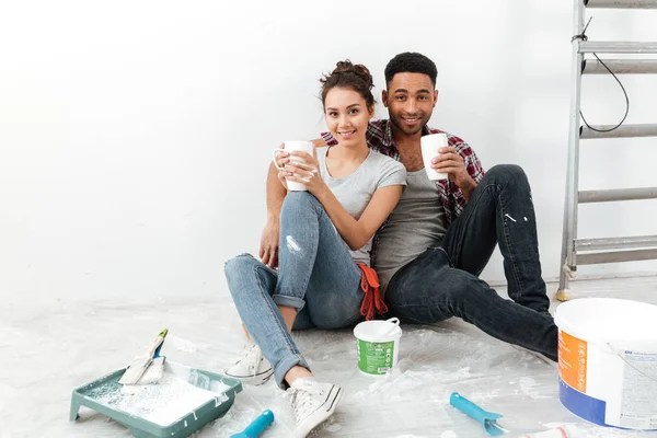 Lyckliga vackra unga paret dricka kaffe och renovera hem — Stockfoto