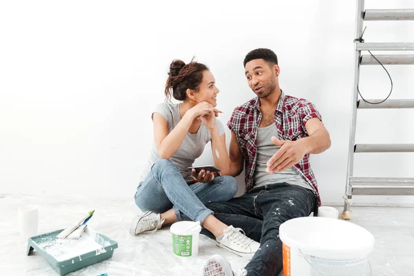 Feliz casal jovem multiétnico renovando casa e usando telefone celular — Fotografia de Stock