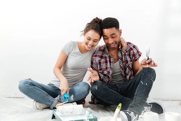 Sorrindo casal amoroso sentado em novo apartamento faz reparação . — Fotografia de Stock