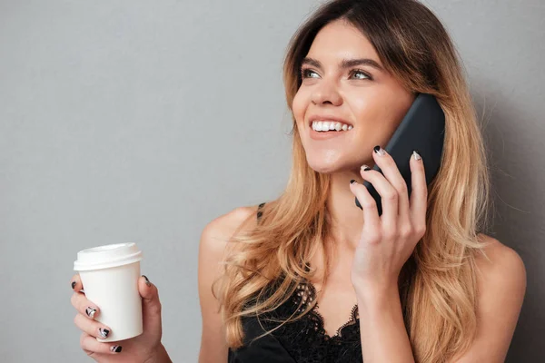 Young woman talking on mobile phone while holding coffee cup — Fotografia de Stock