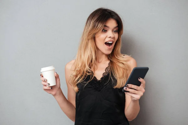 Retrato de uma mulher excited nova que olha o telefone móvel — Fotografia de Stock