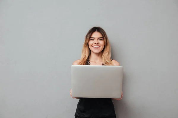 Χαμογελώντας ελκυστική κοπέλα κρατώντας φορητό υπολογιστή και να βλέπουν τα φωτογραφικών μηχανών — Φωτογραφία Αρχείου