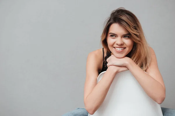 Feliz joven sentada en una silla y posando — Foto de Stock