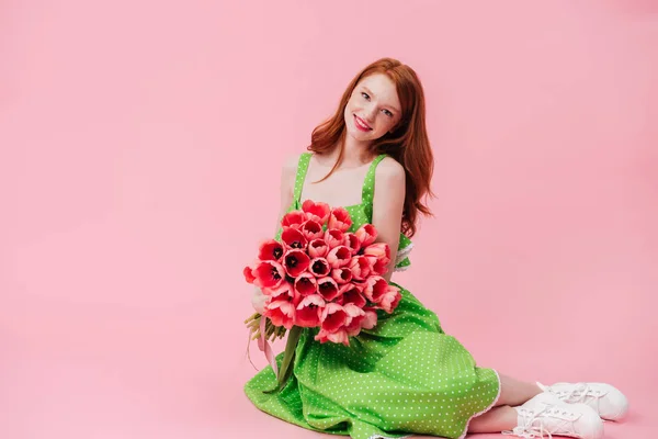 Mulher de sorriso do gengibre que senta-se no assoalho com o ramalhete das flores — Fotografia de Stock