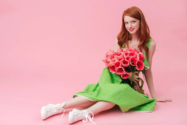 Sorridente donna di bellezza seduta sul pavimento con mazzo di fiori — Foto Stock