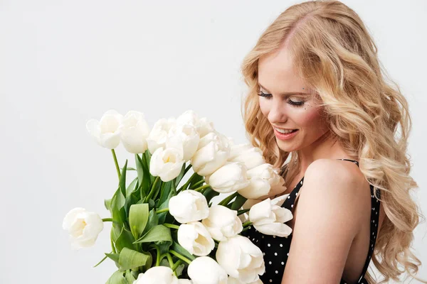 Vista laterale di donna bionda sorridente in posa con fiori bouquet — Foto Stock