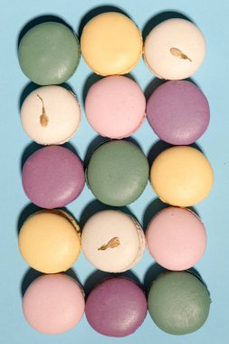 Mavi masa arka plan üzerinde tatlı renkli macaroons.