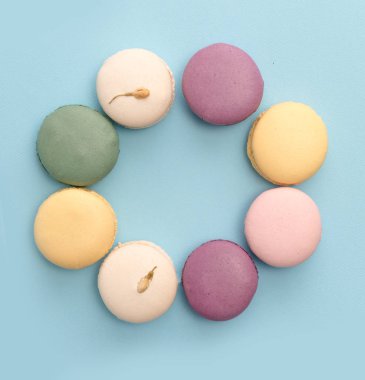 Mavi masa arka plan üzerinde tatlı renkli macaroons.