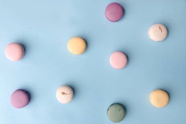 Mavi masa arka plan üzerinde tatlı renkli macaroons.