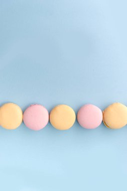 Mavi masa arka plan üzerinde tatlı renkli macaroons.