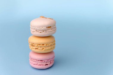 Mavi masa arka plan üzerinde üç tatlı renkli bademli kurabiye.