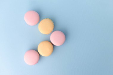 Mavi masa arka plan üzerinde beş tatlı renkli bademli kurabiye.