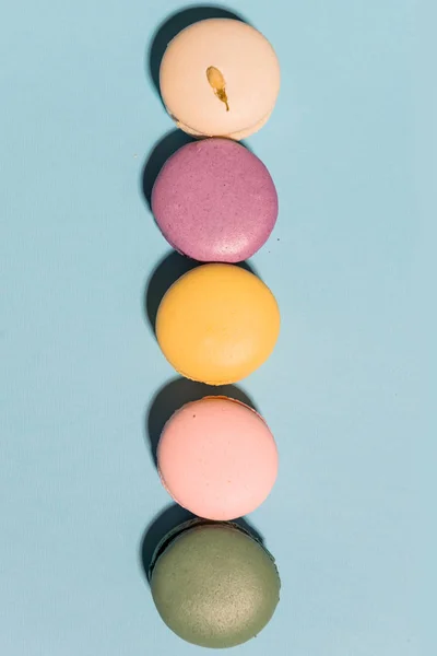 Cinq macarons colorés doux sur fond de table bleu . — Photo