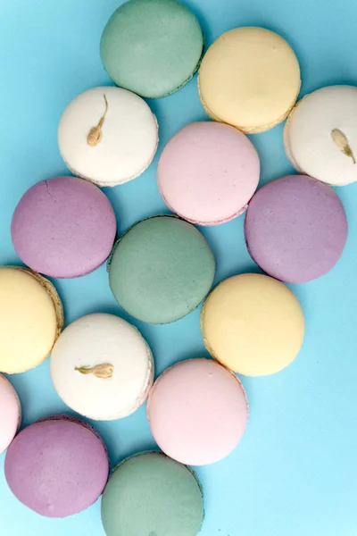 Mavi masa arka plan üzerinde tatlı renkli macaroons. — Stok fotoğraf