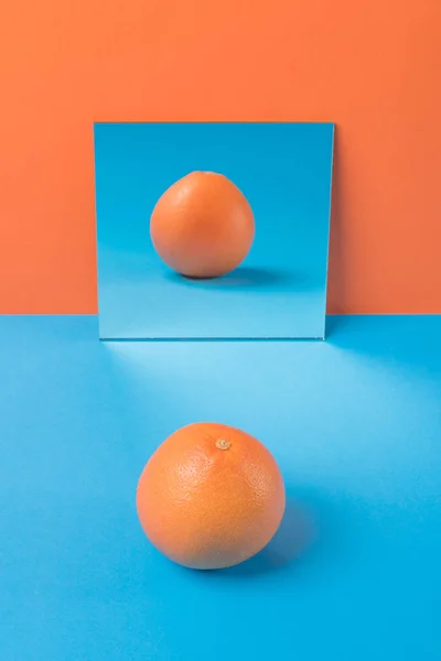 Grapefrukt på blå bord isolerade över orange bakgrund — Stockfoto