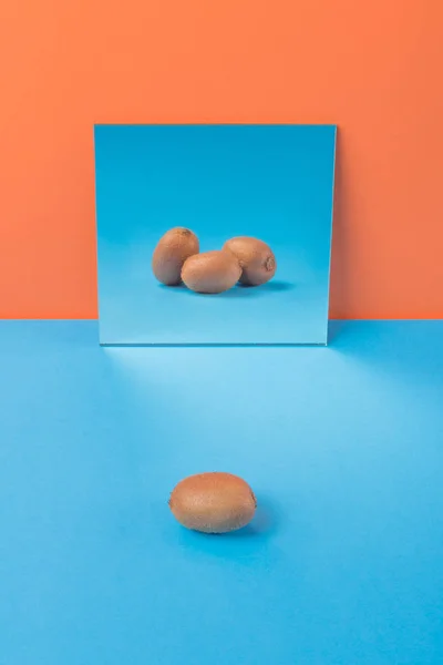 Kiwi på blå bord isolerade över orange bakgrund — Stockfoto