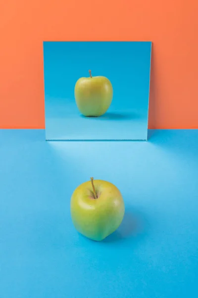 Apple på blå bord isolerade över orange bakgrund — Stockfoto