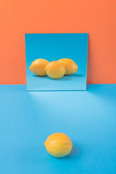 Citron på blå bord isolerade över orange bakgrund — Stockfoto