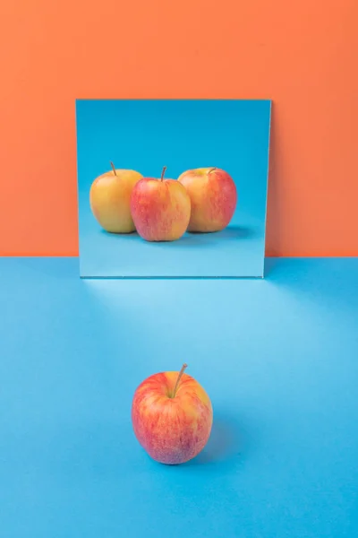 Apple på blå bord isolerade över orange bakgrund — Stockfoto