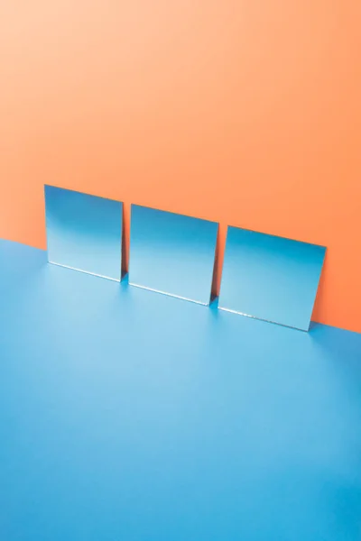 Mirrors on blue table isolated over orange background — Stock Photo, Image