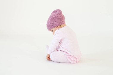 Küçük kız kız yerde oturan şapka giyiyor