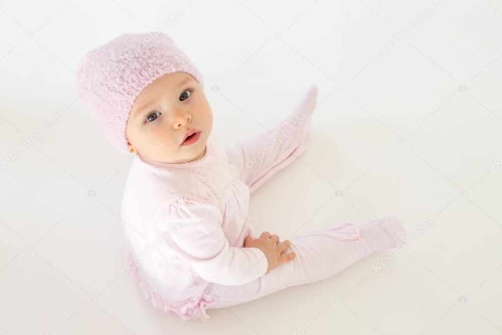 ?ute little baby sitting on floor over white background.