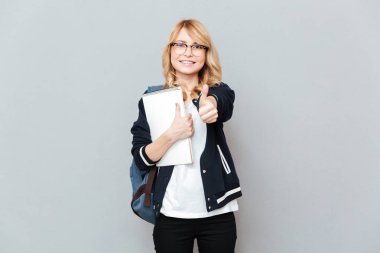 Neşeli genç bayan öğrenci gösterilen defter tutan Yaşasın.