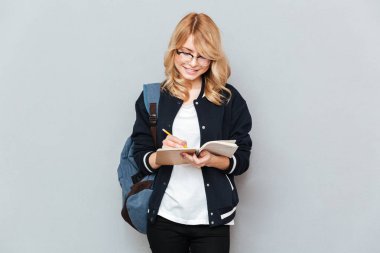 Mutlu genç kadın öğrenci not defterinde yazma.