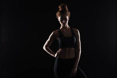 Ciddi genç spor Bayan siyah arka plan üzerinde ayakta