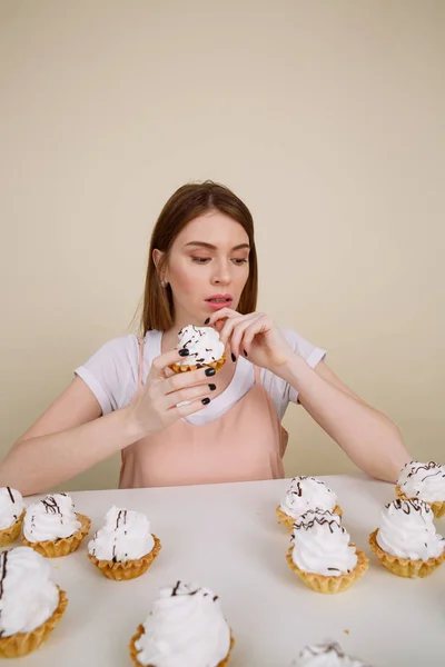 Серйозна молода леді позує, сидячи тримаючи кекс — стокове фото