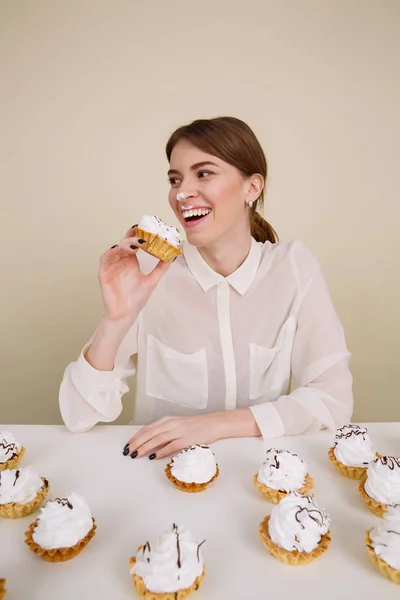 Morsom ung kvinne smiler og spiser kaker – stockfoto