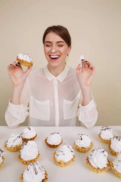 Cheerful funny young woman eating cakes and laughing