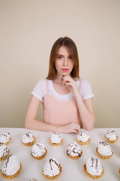 Increíble joven sentada y posando cerca de cupcakes — Foto de Stock