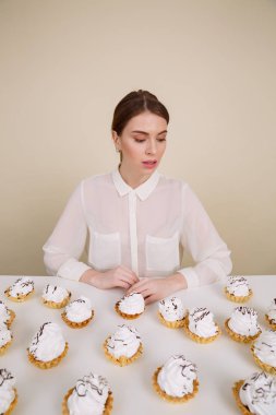 Cupcake yakınındaki otururken poz konsantre genç bayan