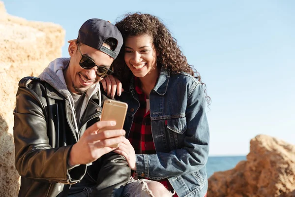 Happy loving couple walking outdoors at beach chatting by phone. — Stock Photo, Image