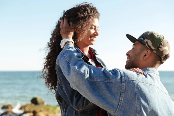 Gelukkig Afrikaanse liefdevolle paar buiten wandelen op strand. — Stockfoto